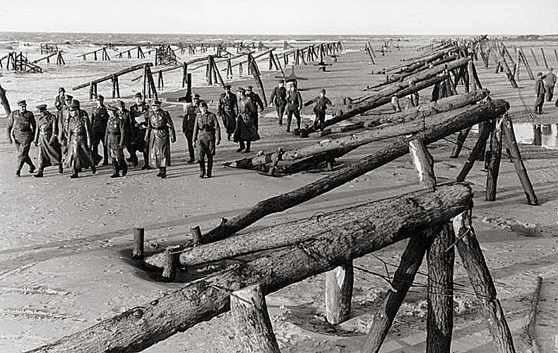 Field Marshal Rommel and officers inspect large landing obstacles along a portion of the Atlantic Wall.