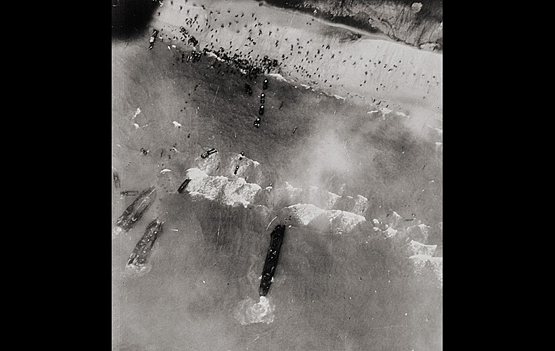 An aerial view of men storming the beaches of Normandy.
