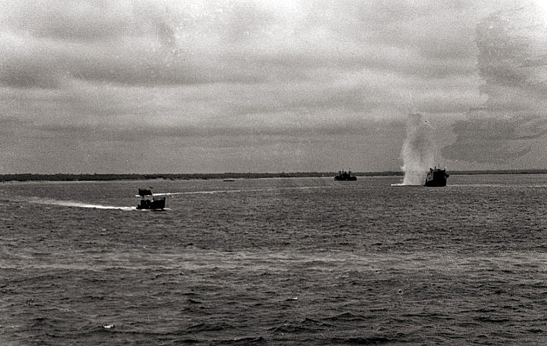 A German shell hits beside a landing craft approaching the beach during the early stages of the landings.