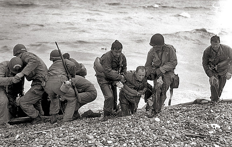 Americans help survivors who reached the shore in a life raft after their landing craft was sunk.