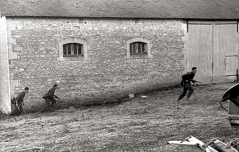 German soldiers dash into position near a barn.