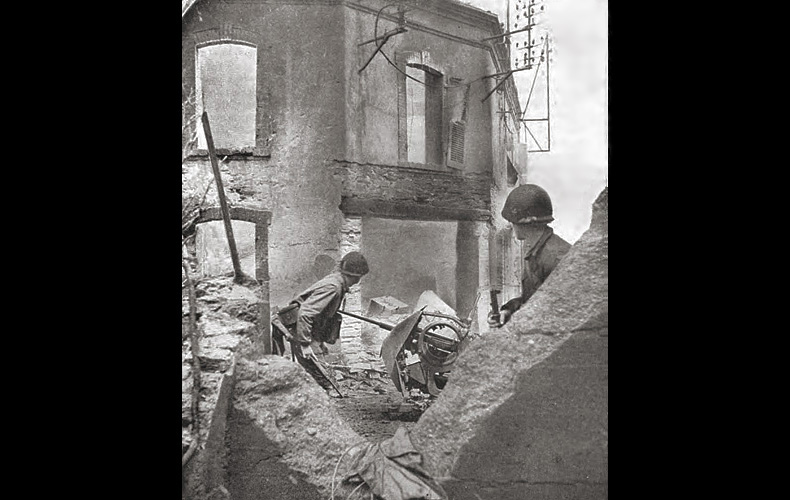In Cherbourg, two infantrymen try to locate German riflemen in a shell-torn building. Street fighting continued most of the day June 26th, but by the end of the day only the arsenal and outer breakwater forts remained in German hands.