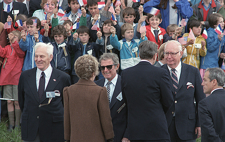 President Reagan and Nancy Reagan chat with D-Day veterans amid a ceremony also attended by French school children.