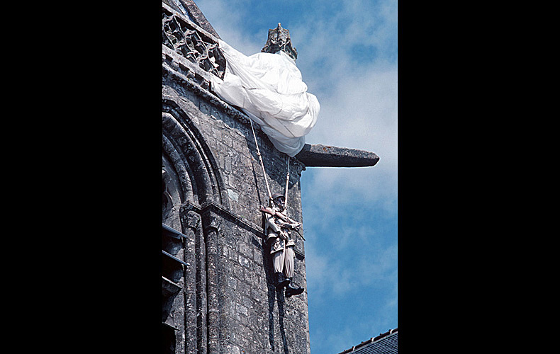 A mannequin dressed as a paratrooper hangs from the corner of a church in Saint-Mere-Eglise, on the very spot where an American Army paratrooper hung for more than a day at the beginning of the invasion, pretending to be dead to avoid being shot or captured by the town's German occupiers.