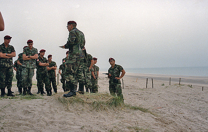 Soldiers of the 82nd Airborne Division listen to a battle account while standing on the invasion beach.