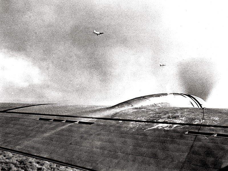 Two Japanese Navy Type 99 Carrier Bombers (Val) fly near a U.S. Army 38th Reconnaissance Squadron B-17 that arrived over Oahu from California in the middle of the air raid. 