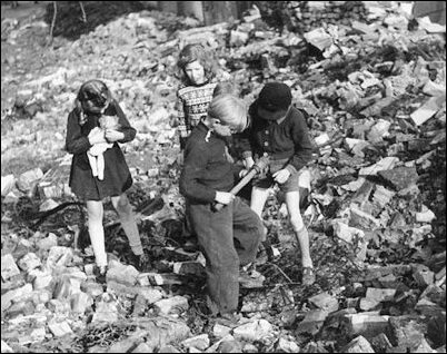 German children playing amid a massive pile of war rubble find an intact hand grenade. 